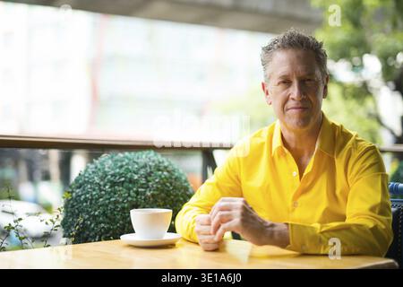 Portrait Of Stylish Mature Handsome Man Sitting In Coffee Shop Stock Photo