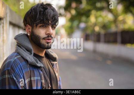 Portrait of young handsome bearded Indian hipster man in the streets outdoors Stock Photo