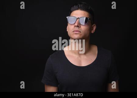 Studio shot of young handsome multi ethnic man against black background Stock Photo
