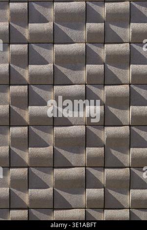 A rhythmic pattern of light and shadow on a modern geometric facade in Vila-real, Villarreal, Castello, Spain, featuring three-dimensional beige tiles Stock Photo