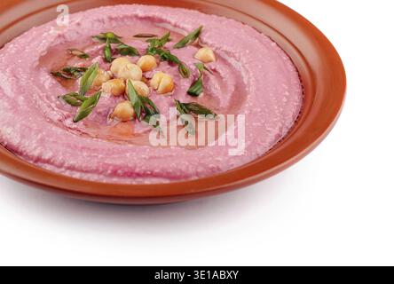 Pink beetroot hummus decorated with chickpeas and green onions, served on a clay dish, isolated on white background Stock Photo