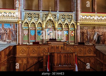 Speaker's podium with Hungarian national flags, heraldic coat of arms wall and historical murals in the main debating chamber, Hungarian Parliament Bu Stock Photo