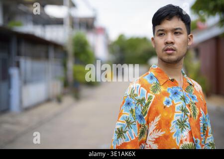 Portrait of young Asian tourist man wearing Hawaiian shirt in the streets outdoors Stock Photo
