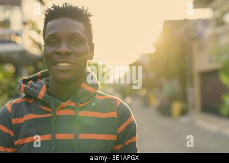 Close up of young happy slim black African man smiling outdoors Stock Photo