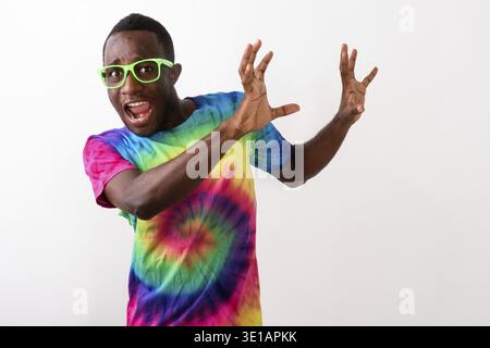 Studio shot of young scared black African man looking afraid and raising his arms against white background Stock Photo