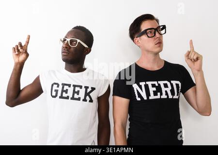 Studio shot of young black African Geek man with European Nerd man thinking and having great idea while pointing finger up against white background Stock Photo