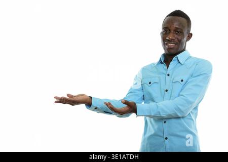 Studio shot of young happy black African man smiling while showing something Stock Photo