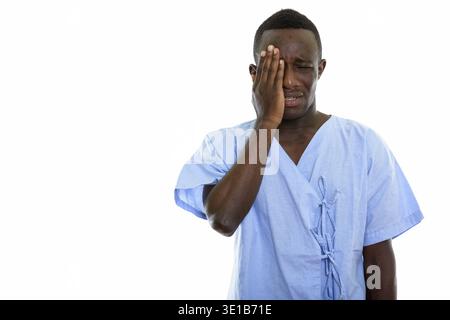Studio shot of young black African man patient looking sad while covering face Stock Photo