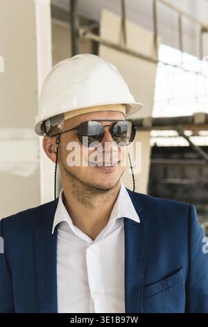 Young man architect or businessman wearing formal suit and hard hat on a construction site Stock Photo