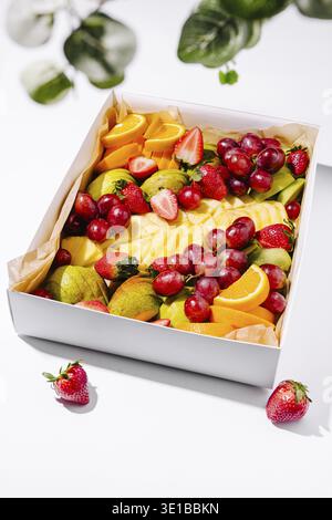 A beautifully arranged box of fresh fruits including strawberries, grapes, oranges, and melons. The colorful display showcases a mix of textures and f Stock Photo