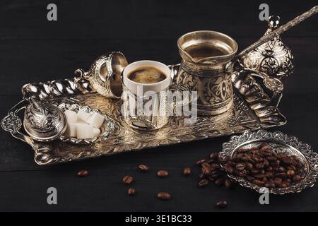 Traditional turkish coffee setup is waiting to be served with its silver pot, cup, sugar bowl and coffee beans on a silver tray Stock Photo