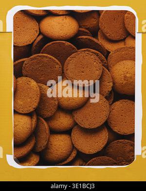 Top view of an open yellow box filled with homemade brown cookies macro Stock Photo