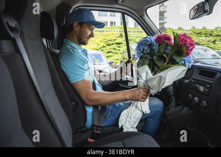 Courier inside the white van during flowers delivery is waiting for a client Stock Photo