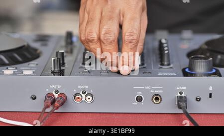 Hand adjusting knobs and faders on a DJ controller, creating music for a festive event Stock Photo