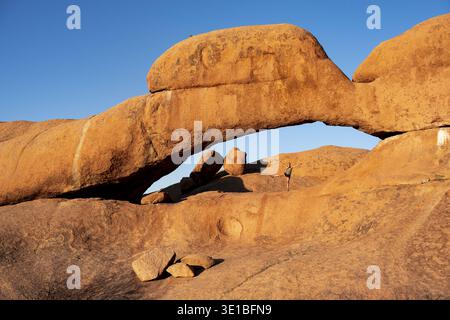 Morning, woman standing in rock arch, Pontok Mountains, Grosse Spitzkoppe, Spitzkoppe, Grosse Spitzkuppe Nature Reserve, Namibia Stock Photo