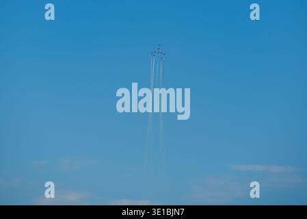 A group of aerobatic jet aircraft flying in perfect formation during an airshow, leaving smoke trails against a clear blue sky during Nato days in Cze Stock Photo