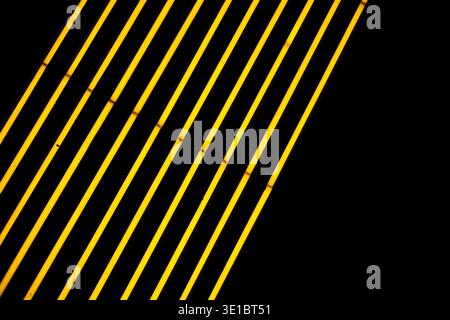 A professional abstract shot featuring rhythmic diagonal lines of vibrant yellow neon lighting. The composition is balanced by a single spotlight cast Stock Photo