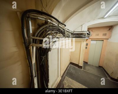 Exposed cabling and electrical wires running along an old building hallway Stock Photo