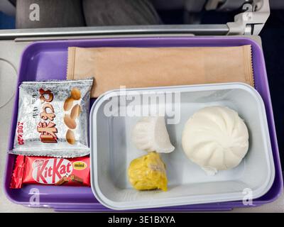Cambodia Air airline tray meal, Asian-style dim sum, dumplings and a steamed bun, KitKat bar and peanuts Stock Photo
