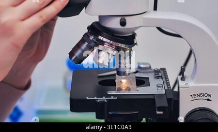 Scientist adjusting microscope, conducting research in laboratory Stock Photo