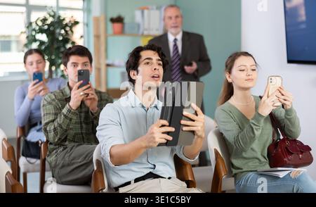 Students scanning QR code or taking photo, professor in background Stock Photo