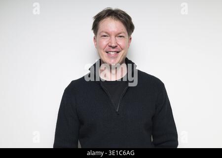 Scandinavian mid adult man smiling in black sweater portrait against white studio background Stock Photo