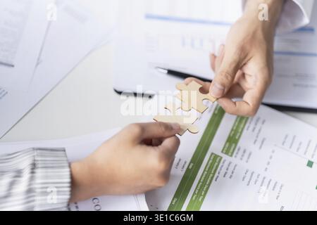 Businessman hands putting together puzzle pieces with Team Building join together and Business Collaboration Concept in office Stock Photo