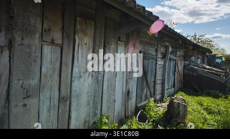 Weathered rustic wooden barn wall at countryside homestead with green grass and blue sky Stock Photo