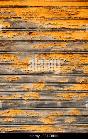 Weathered orange painted wooden planks showing signs of age and decay creating a rustic textured background Stock Photo