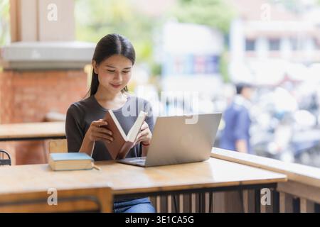 Young Asian Female Student Reading Books in Library Stock Photo