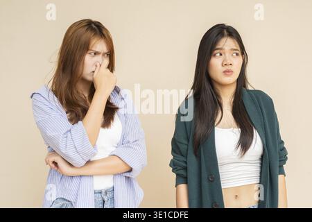 Portrait of two young Asian woman against plain wall Stock Photo