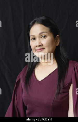 Portrait of stylish mature Asian woman against black studio background Stock Photo