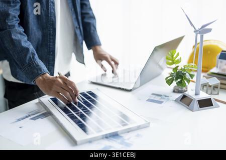 Businessman and Engineers Working on Solar Panels Project for Green Energy Accumulation in Eco-Friendly Office Stock Photo