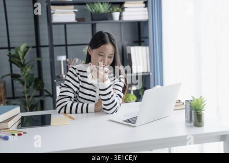 Asian Woman Engaging with Voice Assistant on Smartphone in Modern Home Stock Photo