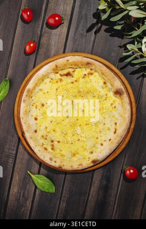 A freshly baked cheese pizza sits on a brown wooden platter, surrounded by cherry tomatoes and fresh spinach leaves. The golden crust and melted chees Stock Photo