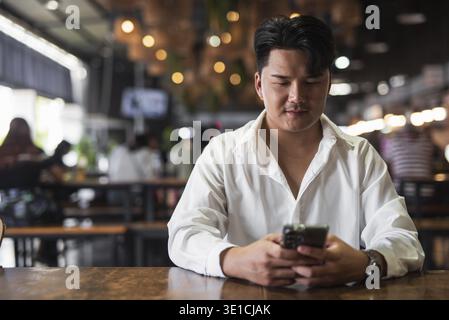 Portrait of Handsome Young Asian Man Sitting in Coffee Shop Restaurant Concept Stock Photo