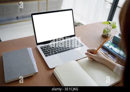Students sitting at desk using laptop blank screen computer working in office mockup image blank screen computer white background Stock Photo
