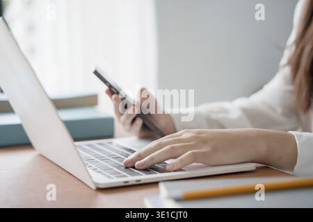 Asian woman using laptop to study student engaged in online learning at college Stock Photo