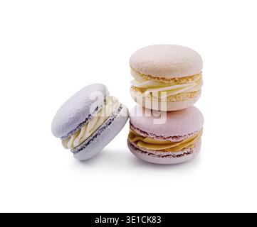 Three macarons in pastel colors are stacked on top of each other. The purple, pink, and yellow treats display creamy fillings, creating an appealing d Stock Photo