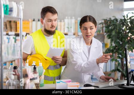 Female pharmacist consults male builder in pharmacy Stock Photo