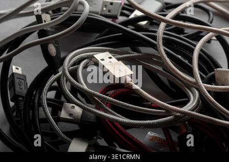 Close up of tangled USB cables and charging cords forming a messy pile of electronic accessories and connectors. Stock Photo