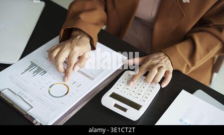Middle age Asian woman Auditor or internal revenue service staff senior business woman checking annual financial elderly woman pressing calculator Stock Photo