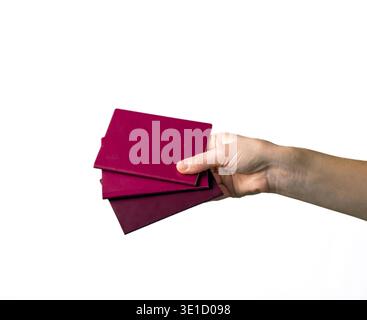 Human hand displaying a stack of burgundy colored business cards against a clean white background. Professional presentation suitable for business and Stock Photo