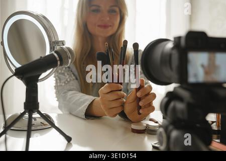 Young woman beauty blogger making a video review of different make-up brushes for her followers Stock Photo