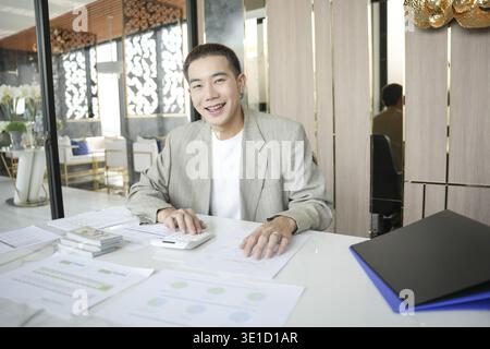 Smiling young Asian businessman in modern office. handsome asian man happy and friendly while working success job Stock Photo
