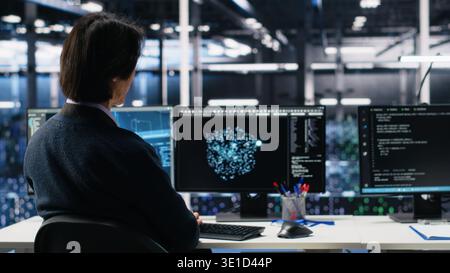 Data center system administrators using machine learning algorithms on PC to analyze datasets. Server farm employees using AI neural networks on devices to recognize data patterns, camera A Stock Photo