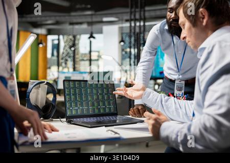 Diverse professionals cooperating on monthly financial report, analyzing key data to improve productivity and teamwork. Multiethnic coworkers using laptop in analyzing company stock performance. Stock Photo