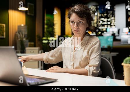 Engaged executive manager researching market data and developing strategy to meet business goals, using spreadsheets for proofreading. Late night work in a multinational company. Stock Photo