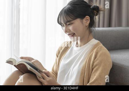 Asian Women reading book and relaxing at home and comfort in front of opened book Stock Photo