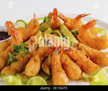 Golden fried shrimp served with slices of fresh lime and dipping sauce, garnished with herbs Stock Photo